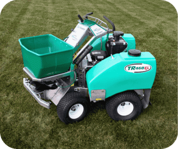 Lawn care machine with a green hopper and labeled "TR460XL" parked on freshly cut grass.