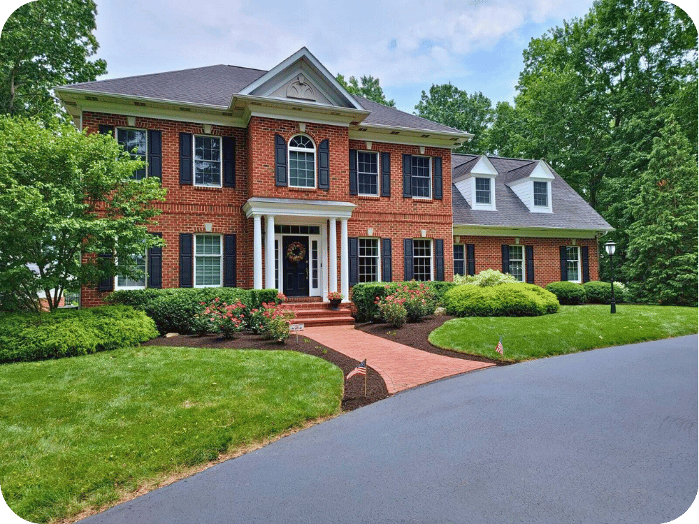 Red brick colonial-style house with black shutters, white trim, and well-maintained landscaping.