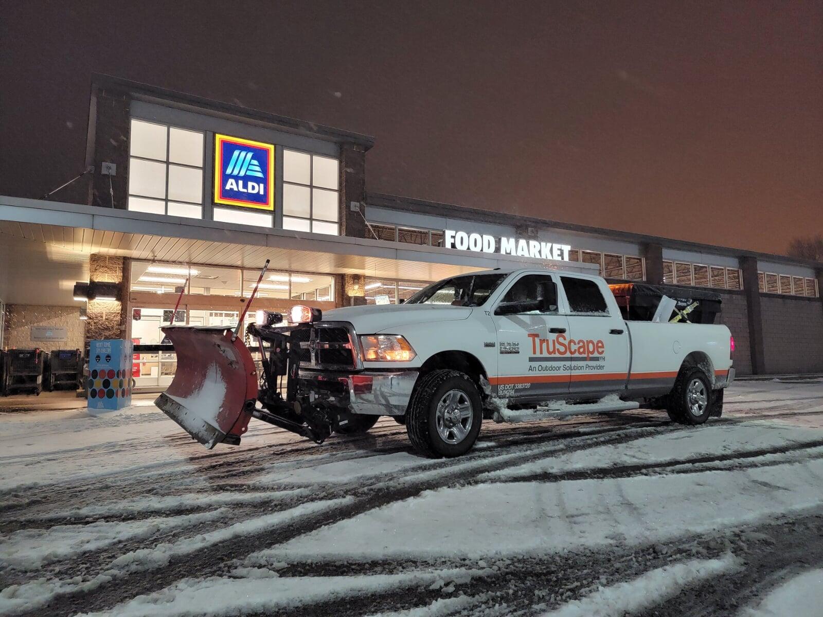 A sidewalk snow removal tractor clears a few inches of snow from a property.