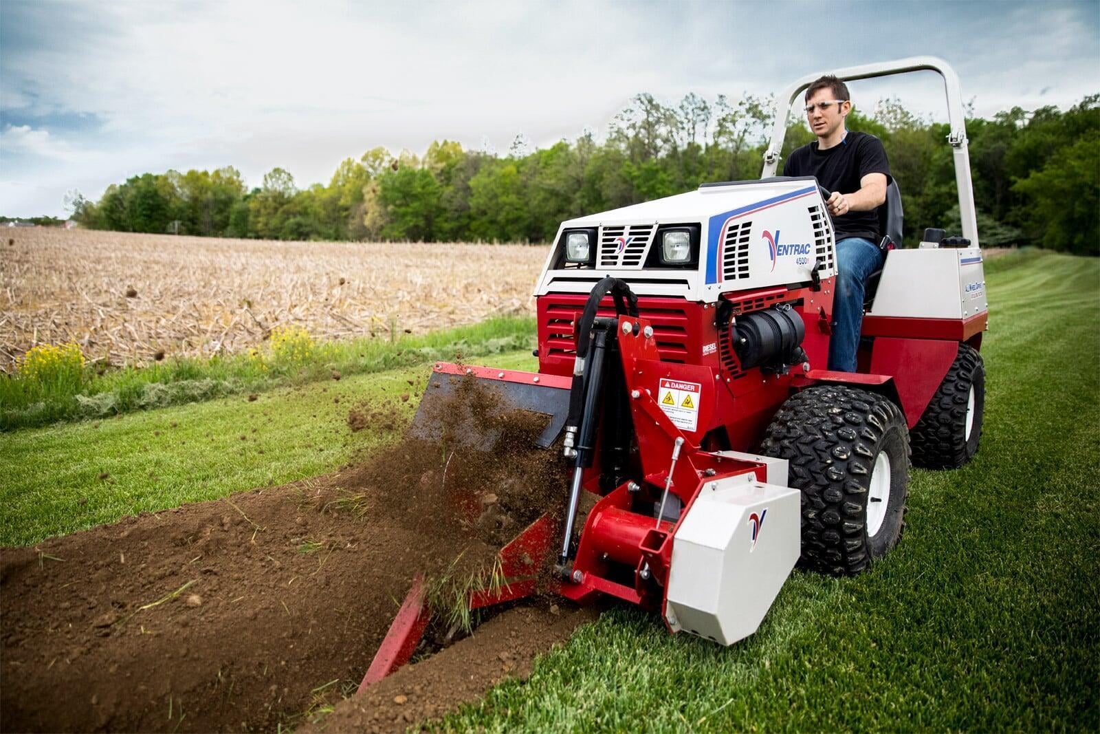 A person in a black shirt on a tractor performing a trenching project. 