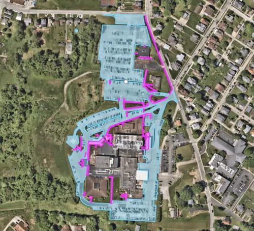 An aerial map showing a commercial property with highlighted snow removal routes and parking areas in blue and pink.